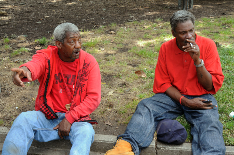 Sitting on the grass in Moore Square, Larry Underwood, left, says he sleeps outdoors and Samuel L. Johnson, right, has a place to live on Avent Ferry Road. 