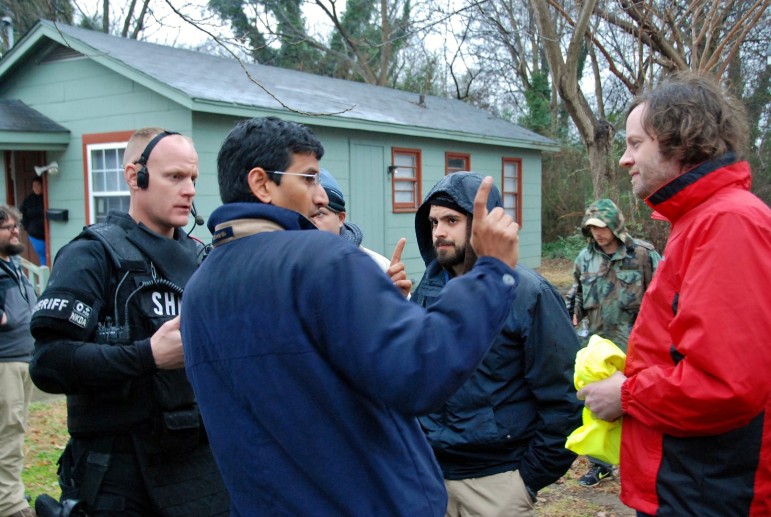 Director Rob Underhill, right, and Camera Operator Henry Ceiro center, listen to Director of Photography Aravind Ragupathi, fore, about how the camera will be filming the scene. Behind them, Wake County Sheriff Special Response Team Member Frankie Eagles IV waits for direction.