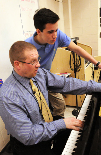 Teacher Brad Benson, left, works at the piano with senior Stephen Howard.