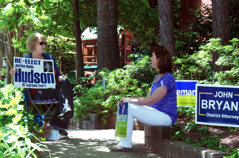 Campaign workers, Diana Koenning, left and Anna Tilghman, chat in the shade as they wait for voters to arrive at the Unitarian Universalist church polling place.